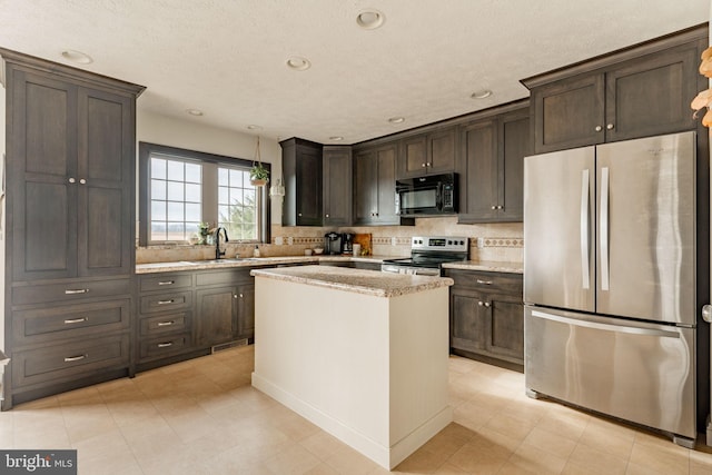 kitchen featuring stainless steel appliances, dark brown cabinets, a sink, and light stone countertops