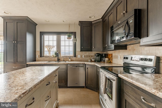 kitchen with recessed lighting, decorative backsplash, appliances with stainless steel finishes, a sink, and dark brown cabinets