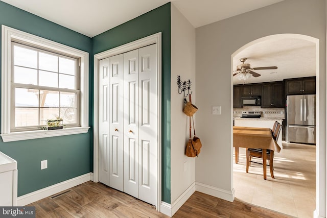 entryway with light wood-style floors, arched walkways, visible vents, and baseboards