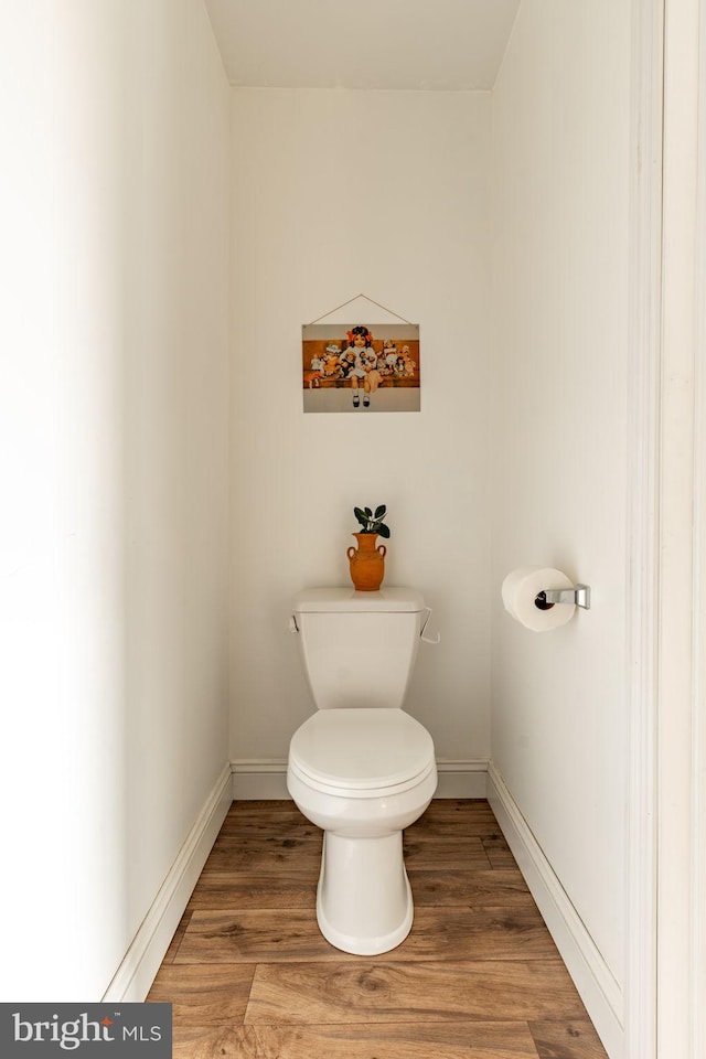 bathroom with toilet, baseboards, and wood finished floors