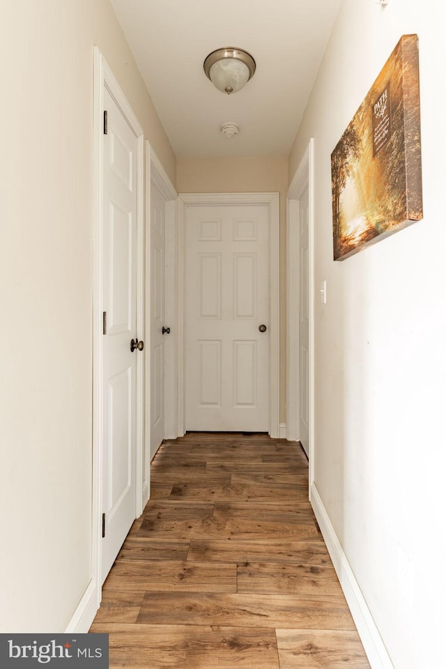 hall with light wood-type flooring and baseboards