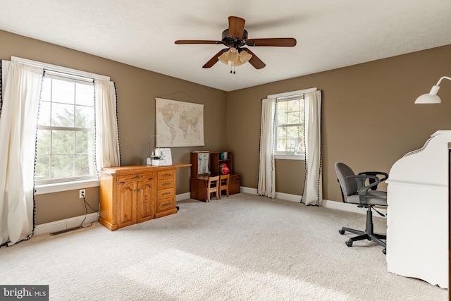 office area with baseboards, visible vents, a ceiling fan, and light colored carpet