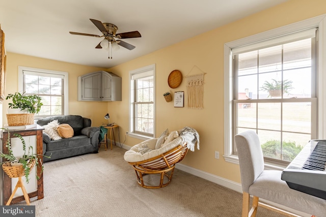 living area with carpet flooring, ceiling fan, and baseboards