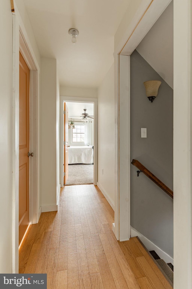 hall with light wood-type flooring and baseboards