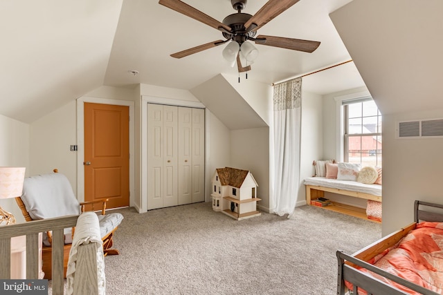 bedroom featuring carpet, lofted ceiling, a closet, visible vents, and a ceiling fan