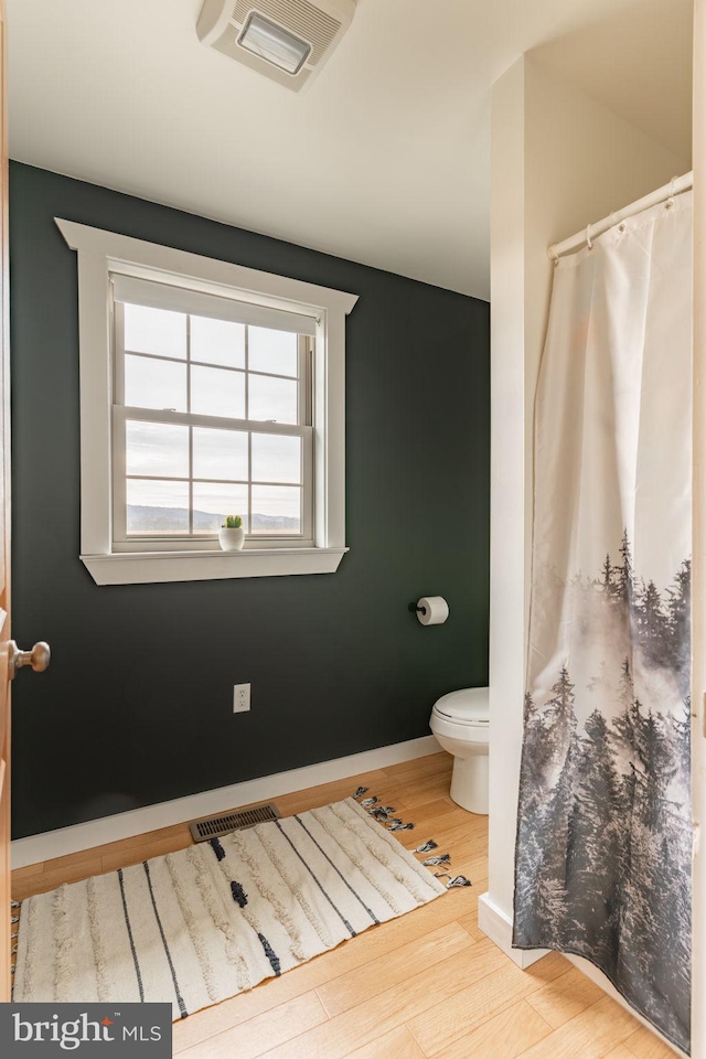 bathroom with toilet, baseboards, visible vents, and wood finished floors