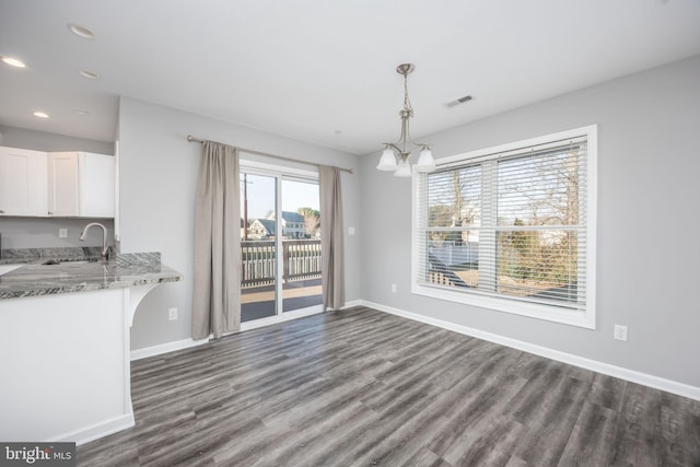 unfurnished dining area featuring a sink, visible vents, baseboards, and a chandelier