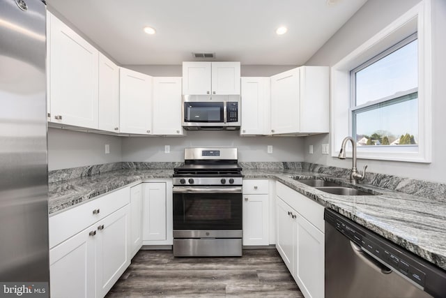 kitchen featuring dark wood finished floors, white cabinetry, stainless steel appliances, and a sink