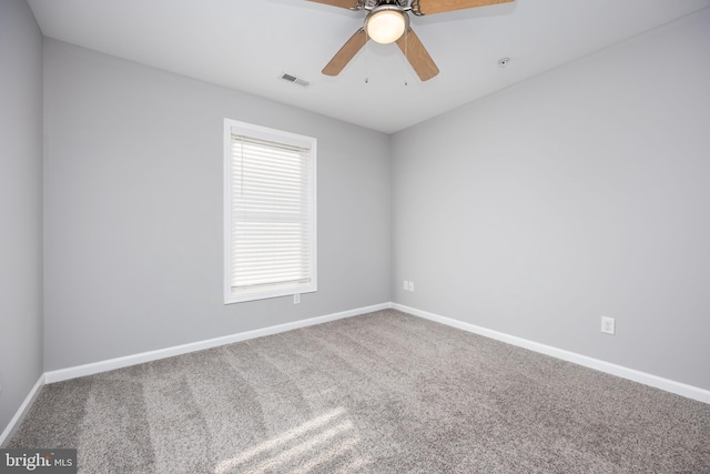 carpeted spare room featuring a ceiling fan, visible vents, and baseboards