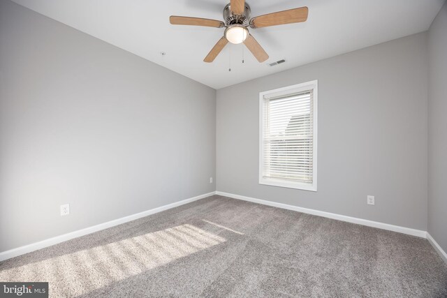 carpeted empty room with visible vents, a ceiling fan, and baseboards