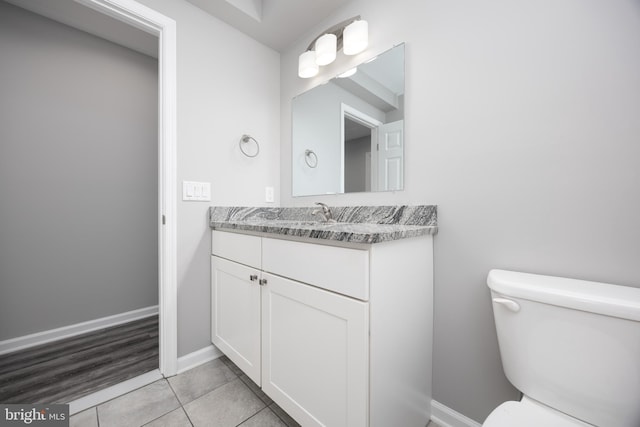 bathroom featuring tile patterned floors, baseboards, toilet, and vanity