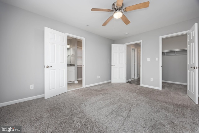 unfurnished bedroom featuring a walk in closet, baseboards, and carpet floors