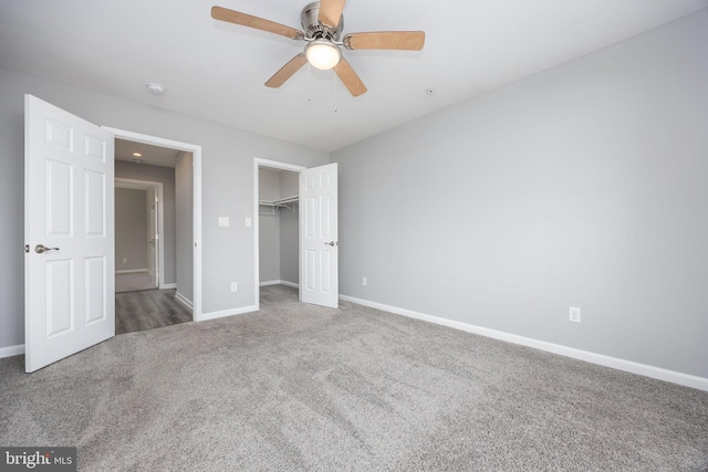 unfurnished bedroom with a ceiling fan, baseboards, a closet, a walk in closet, and carpet flooring