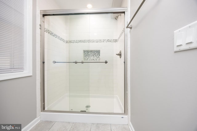 full bathroom featuring tile patterned flooring, a shower stall, and baseboards