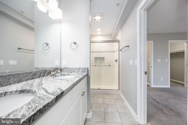 bathroom with baseboards, double vanity, a stall shower, tile patterned floors, and a sink