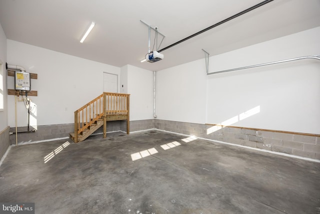 garage with water heater, concrete block wall, and a garage door opener