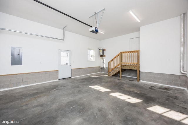 garage with concrete block wall, electric panel, and a garage door opener