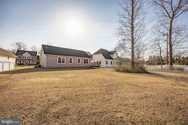 rear view of house featuring a lawn and fence