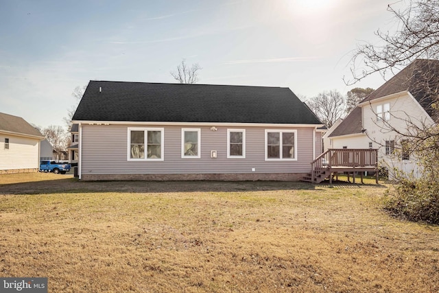 rear view of property with a yard, a wooden deck, and a shingled roof