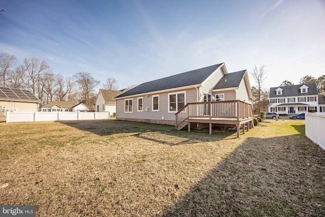 back of property featuring a yard, a residential view, a deck, and fence