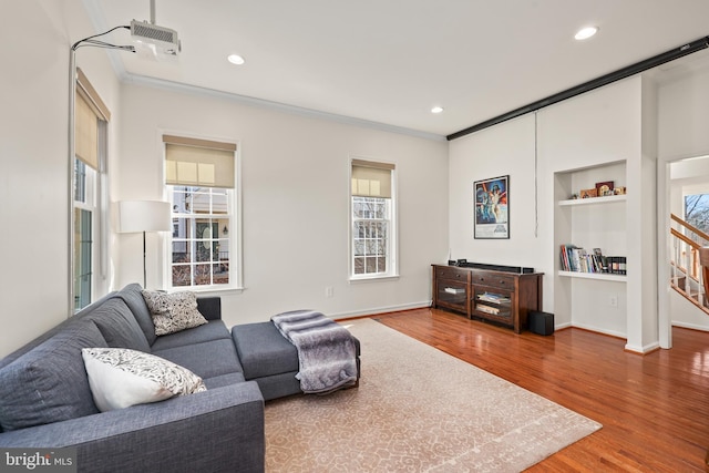 living room with built in shelves, crown molding, recessed lighting, wood finished floors, and baseboards