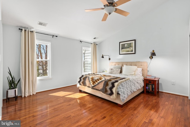 bedroom with hardwood / wood-style flooring, baseboards, visible vents, and vaulted ceiling