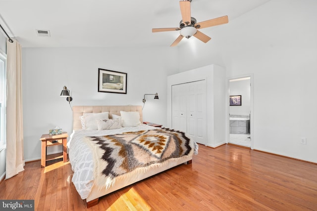 bedroom with visible vents, wood finished floors, ensuite bathroom, vaulted ceiling, and a closet