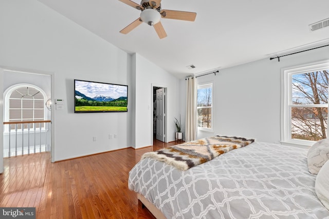 bedroom featuring a spacious closet, visible vents, vaulted ceiling, and wood finished floors