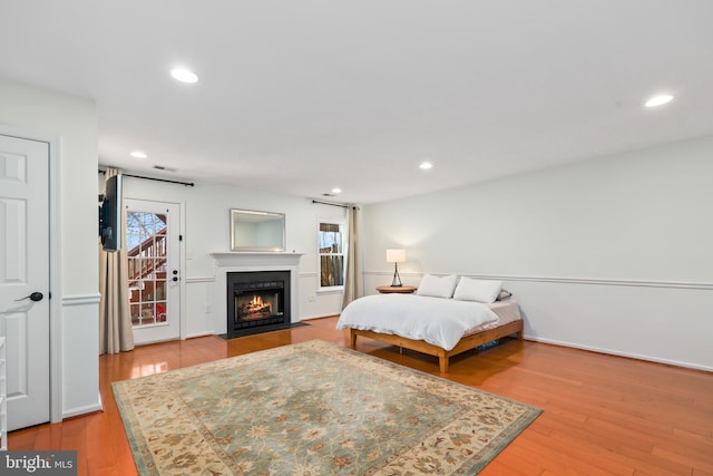 bedroom with multiple windows, wood-type flooring, a fireplace with flush hearth, and visible vents