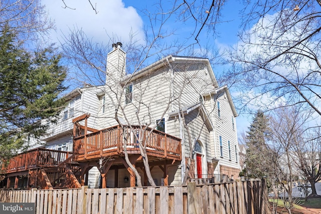 back of property with a fenced front yard, a chimney, and a deck