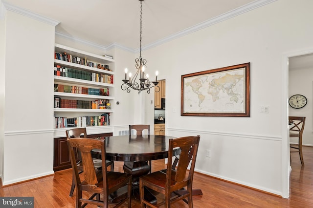 dining space with built in features, a notable chandelier, crown molding, light wood-type flooring, and baseboards