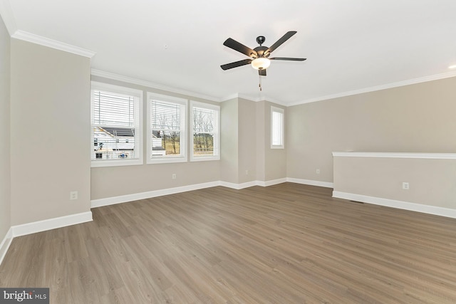 spare room with baseboards, wood finished floors, a ceiling fan, and crown molding