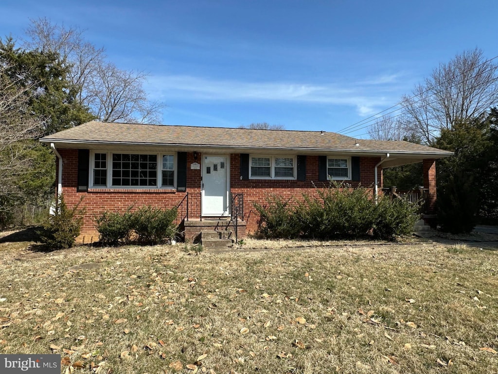 single story home with a front lawn, an attached carport, and brick siding