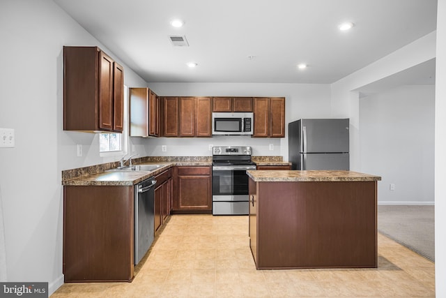 kitchen featuring visible vents, appliances with stainless steel finishes, a sink, a kitchen island, and baseboards