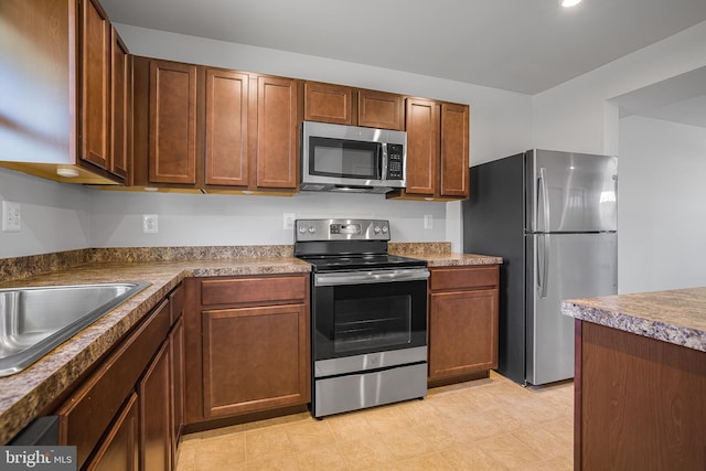 kitchen with stainless steel appliances, brown cabinetry, and dark countertops