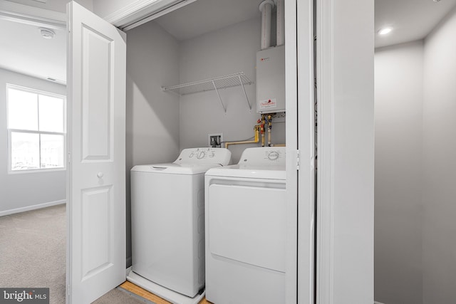 laundry area featuring light carpet, laundry area, baseboards, washing machine and clothes dryer, and tankless water heater