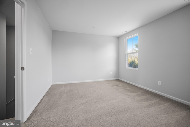 spare room featuring carpet and baseboards