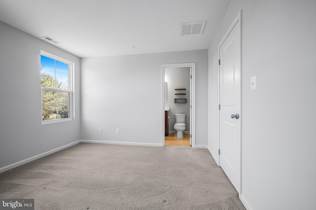 unfurnished bedroom with light carpet, ensuite bathroom, visible vents, and baseboards