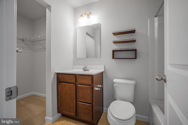 bathroom featuring toilet, a spacious closet, baseboards, and vanity