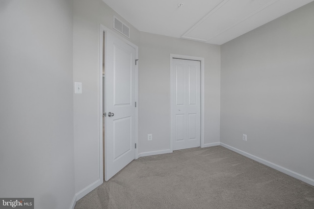 unfurnished bedroom featuring light colored carpet, a closet, visible vents, and baseboards