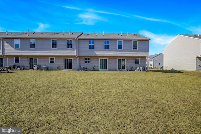 rear view of property with a lawn and cooling unit