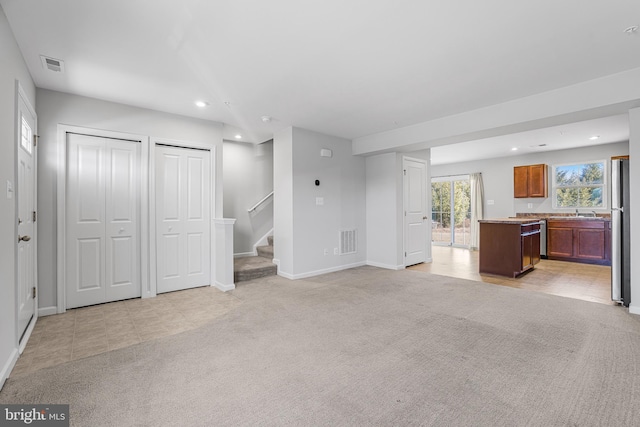 unfurnished living room with recessed lighting, light carpet, visible vents, and stairs