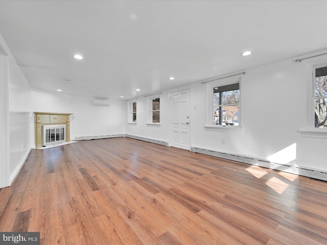 unfurnished living room featuring a baseboard radiator, wood finished floors, an AC wall unit, baseboard heating, and a glass covered fireplace