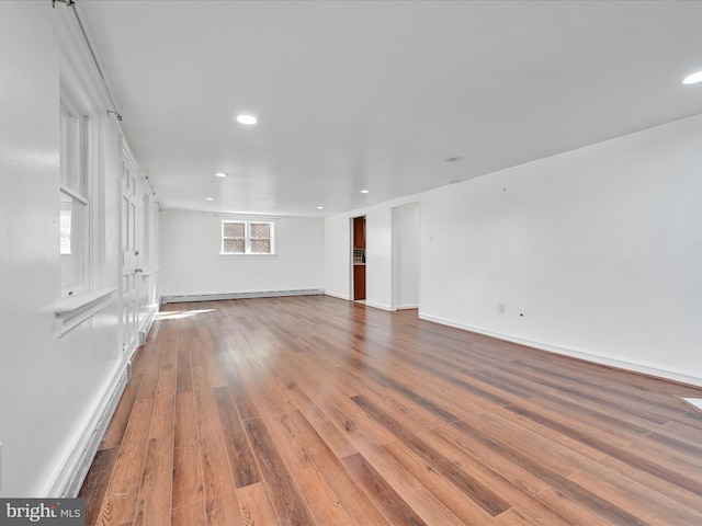 unfurnished living room featuring baseboards, baseboard heating, wood finished floors, and recessed lighting