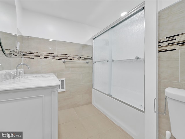 bathroom featuring enclosed tub / shower combo, tile patterned flooring, visible vents, vanity, and tile walls