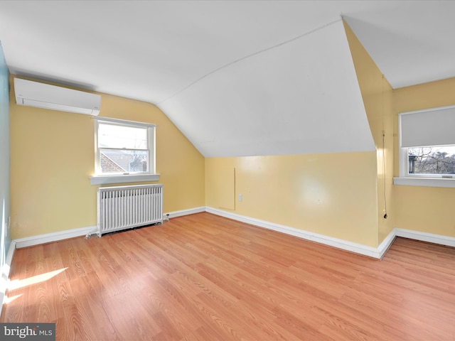 bonus room featuring a wealth of natural light, a wall unit AC, radiator heating unit, and wood finished floors