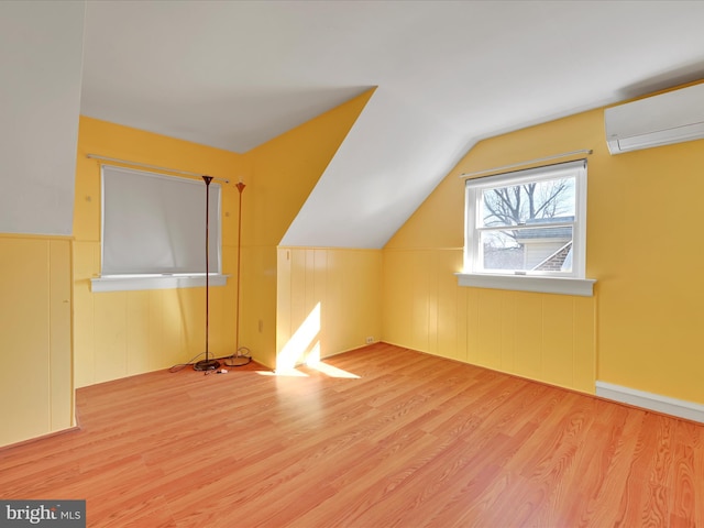 bonus room featuring lofted ceiling, a wall mounted AC, and wood finished floors