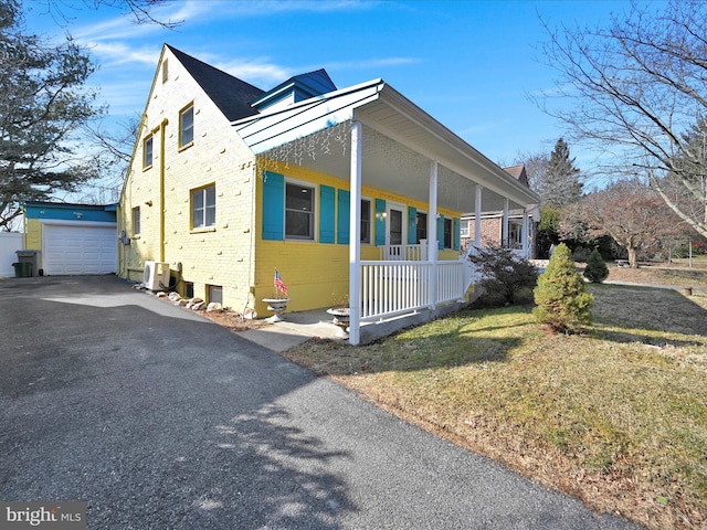 view of front of home featuring brick siding, a porch, a garage, an outdoor structure, and a front lawn