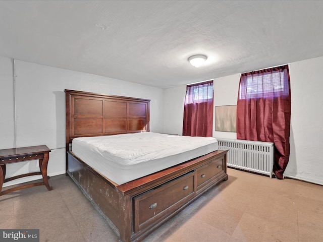 bedroom with light floors, baseboards, and radiator heating unit