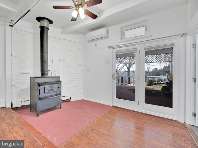 living room with beam ceiling, a wall mounted AC, a wood stove, brick wall, and wood finished floors